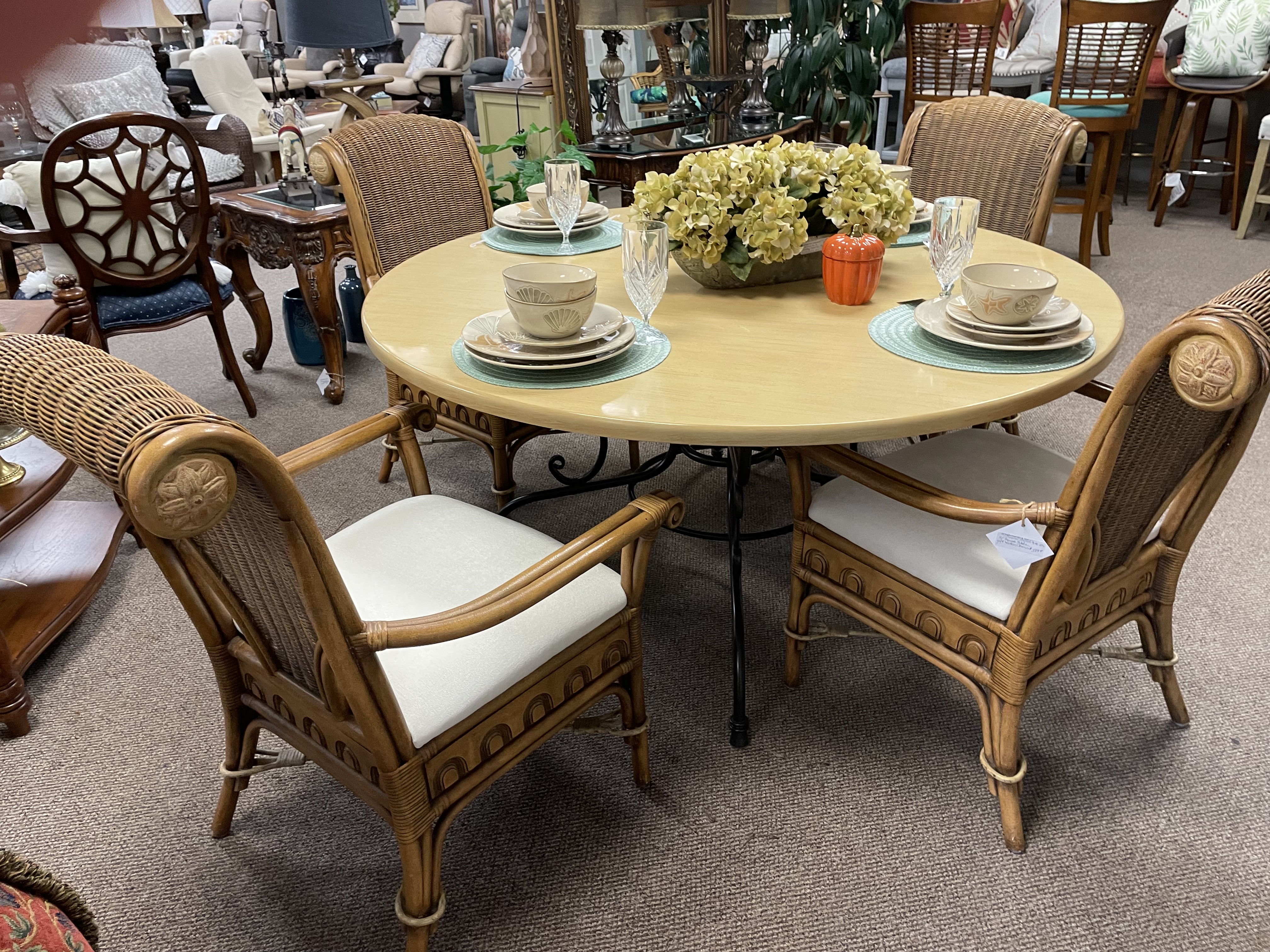 Casual wooden round 4-person dining table with wooden and wicker chairs.