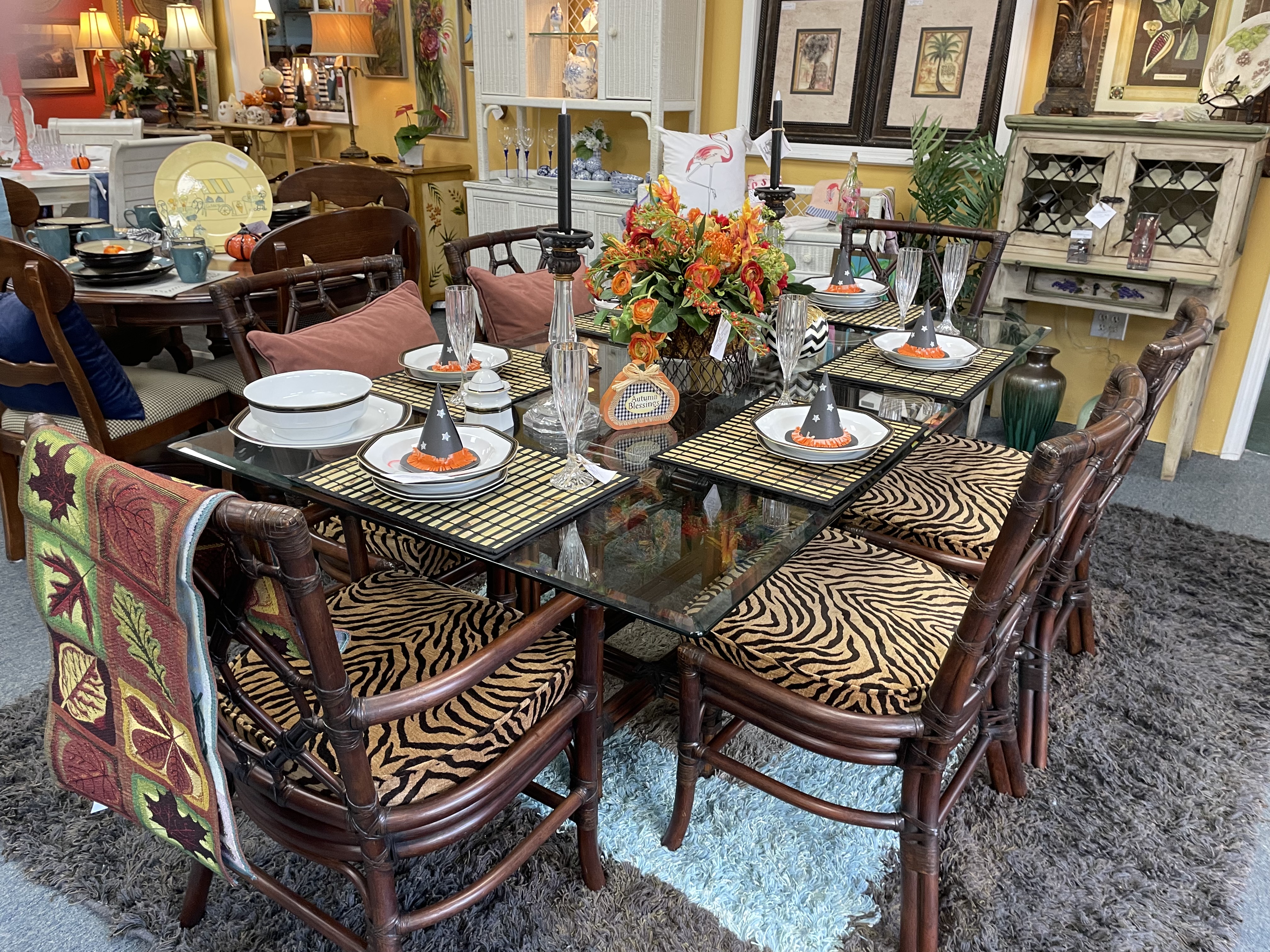 Glass 6-person safari themed dining room table and chairs with animal print seat cushions and place settings and centerpies