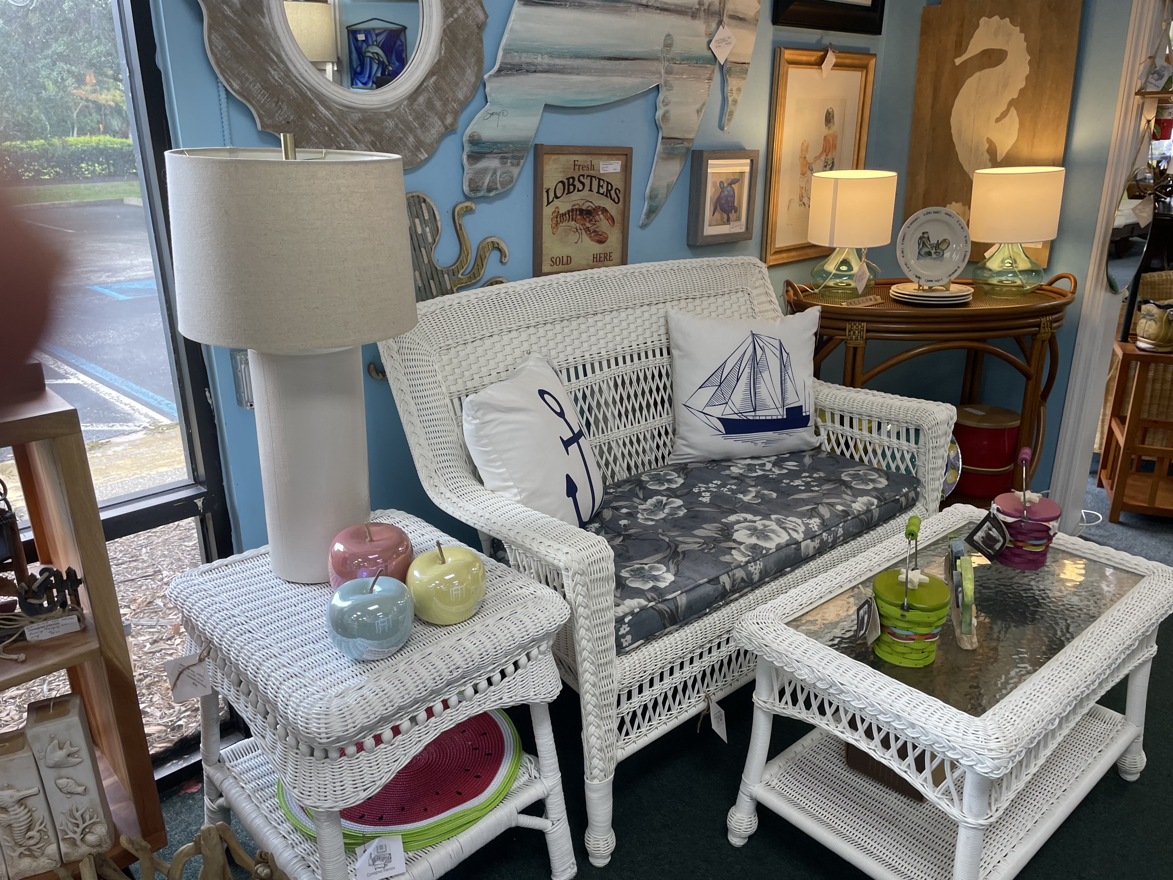 White wicker loveseat with wicker coffee table and end table and ornamental accessories on top of it