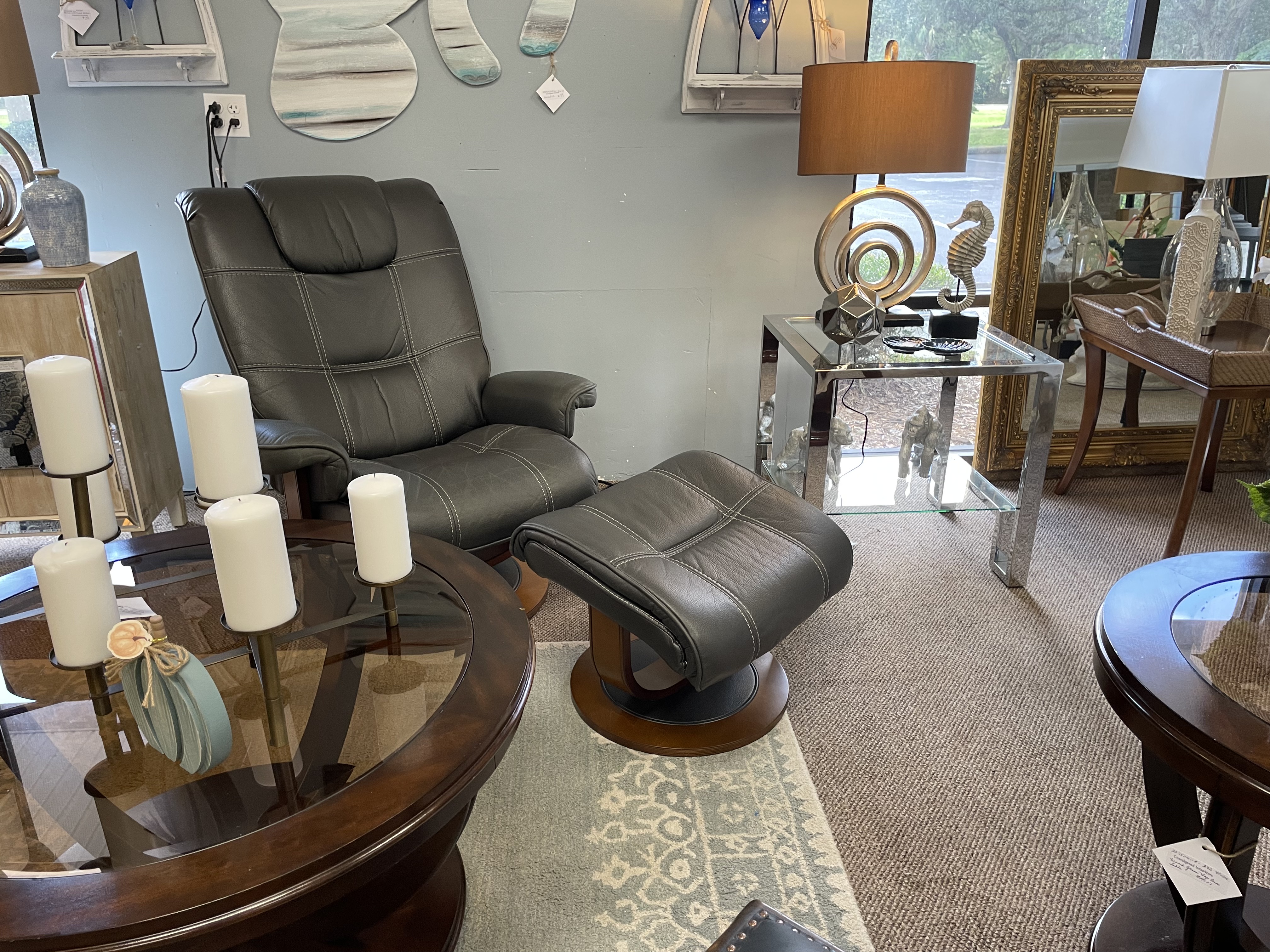 black leather chair with ottomon, a wooden and glass table and an ornamental lamp